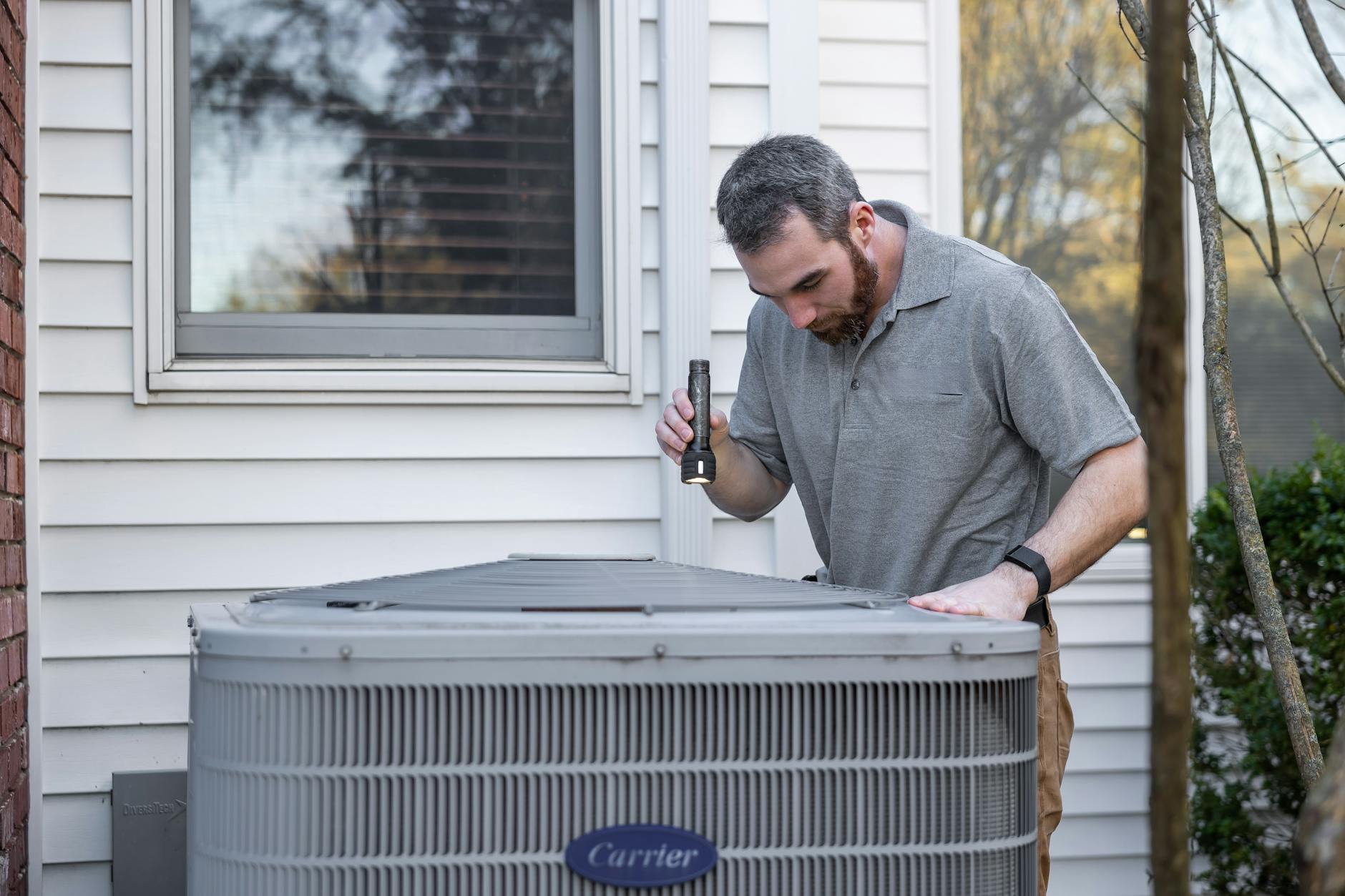 HVAC technician inspecting an outdoor heat pump unit for maintenance