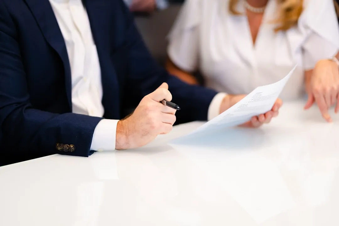 Two people sitting across a table reviewing business documents during a professional negotiation meeting