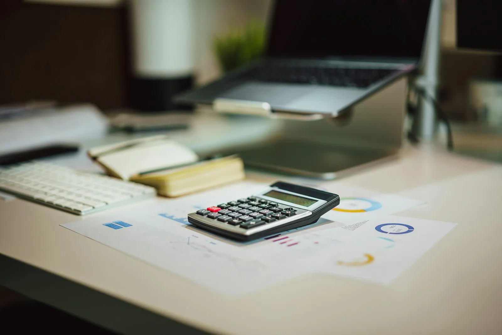 Financial analysis with calculator and laptop showing declining revenue charts
