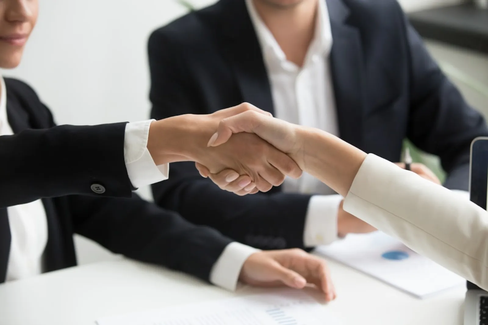 Business deal closing with handshake and signing documents